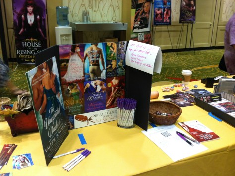Table-top tri-fold display of Regency book covers, with promo swag including pens and bookmarks.