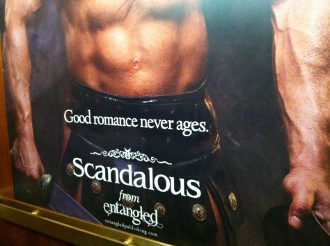 Very large (over life size) poster covering rear wall of elevator; depicts a bare-chested white man in a kilt with the tagline "good romance never ages"